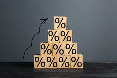 Image of Percent signs on wooden cubes and arrow against grey background