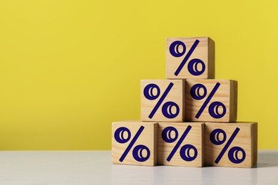 Image of Percent signs on wooden cubes against yellow background. Space for text
