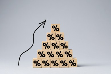 Image of Percent signs on wooden cubes and arrow against grey background