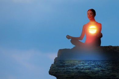 Image of Practicing yoga in nature. Woman meditating in lotus position on cliff. Double exposure with seascape at sunset