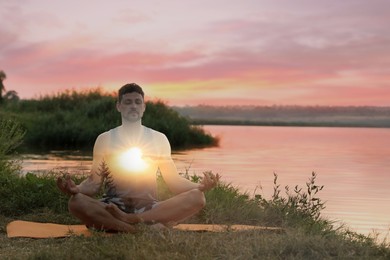 Image of Practicing yoga in nature. Man meditating in lotus position on river shore. Double exposure with landscape at sunrise