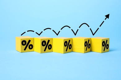 Image of Percent signs on yellow cubes and arrow against light blue background