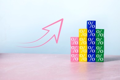 Image of Percent signs on colorful cubes and arrow against light background