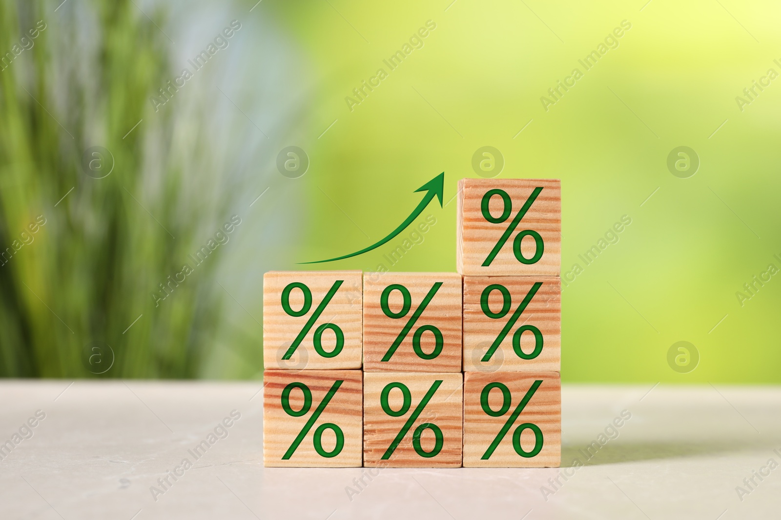 Image of Percent signs on wooden cubes and arrow against blurred green background