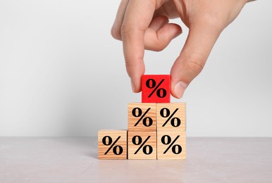 Image of Man putting red cube with percent sign onto others against white background, closeup