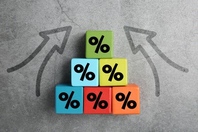 Image of Colorful cubes with percent signs and arrows on grey textured background, top view