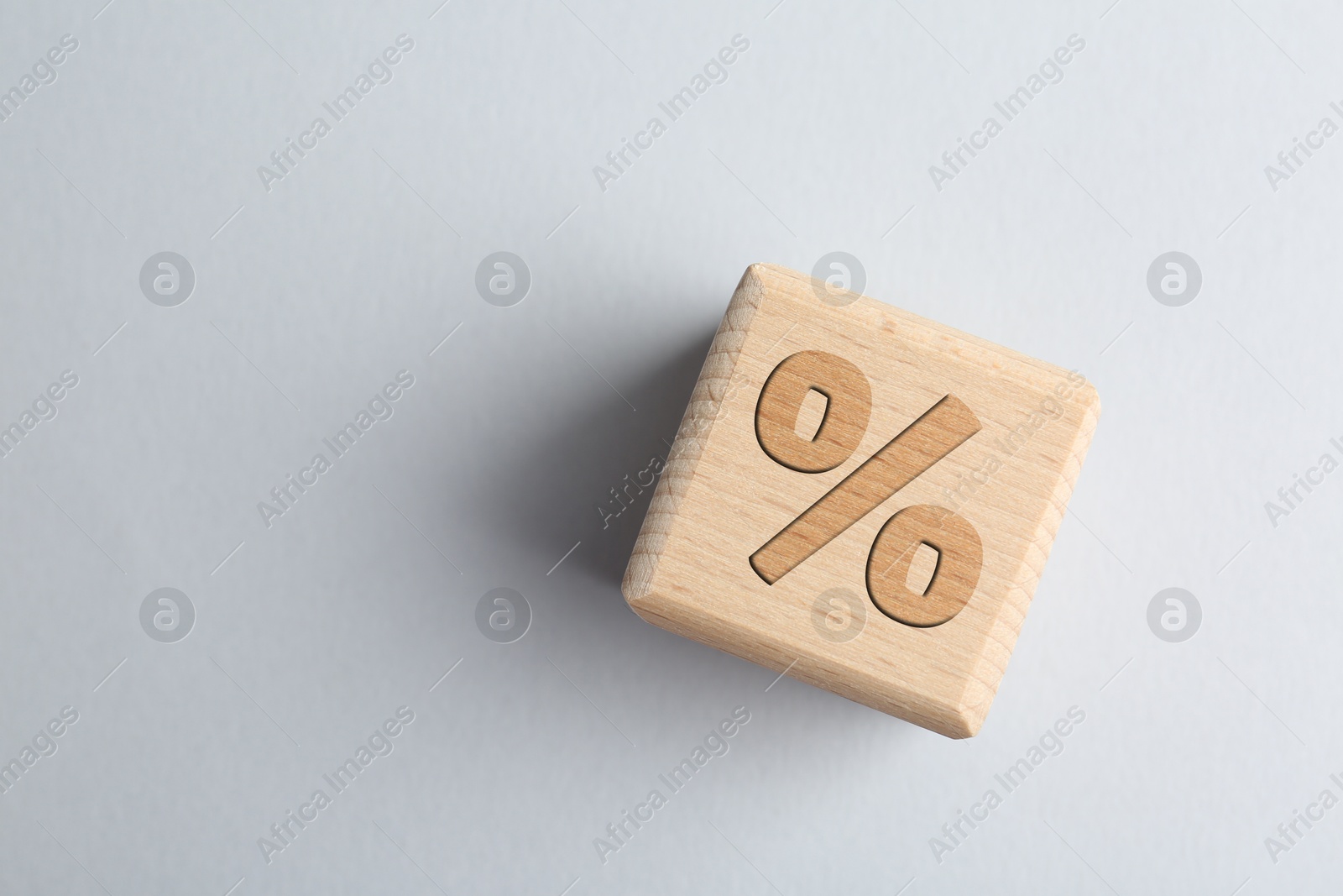 Image of Wooden cube with percent sign on light grey background, top view. Space for text