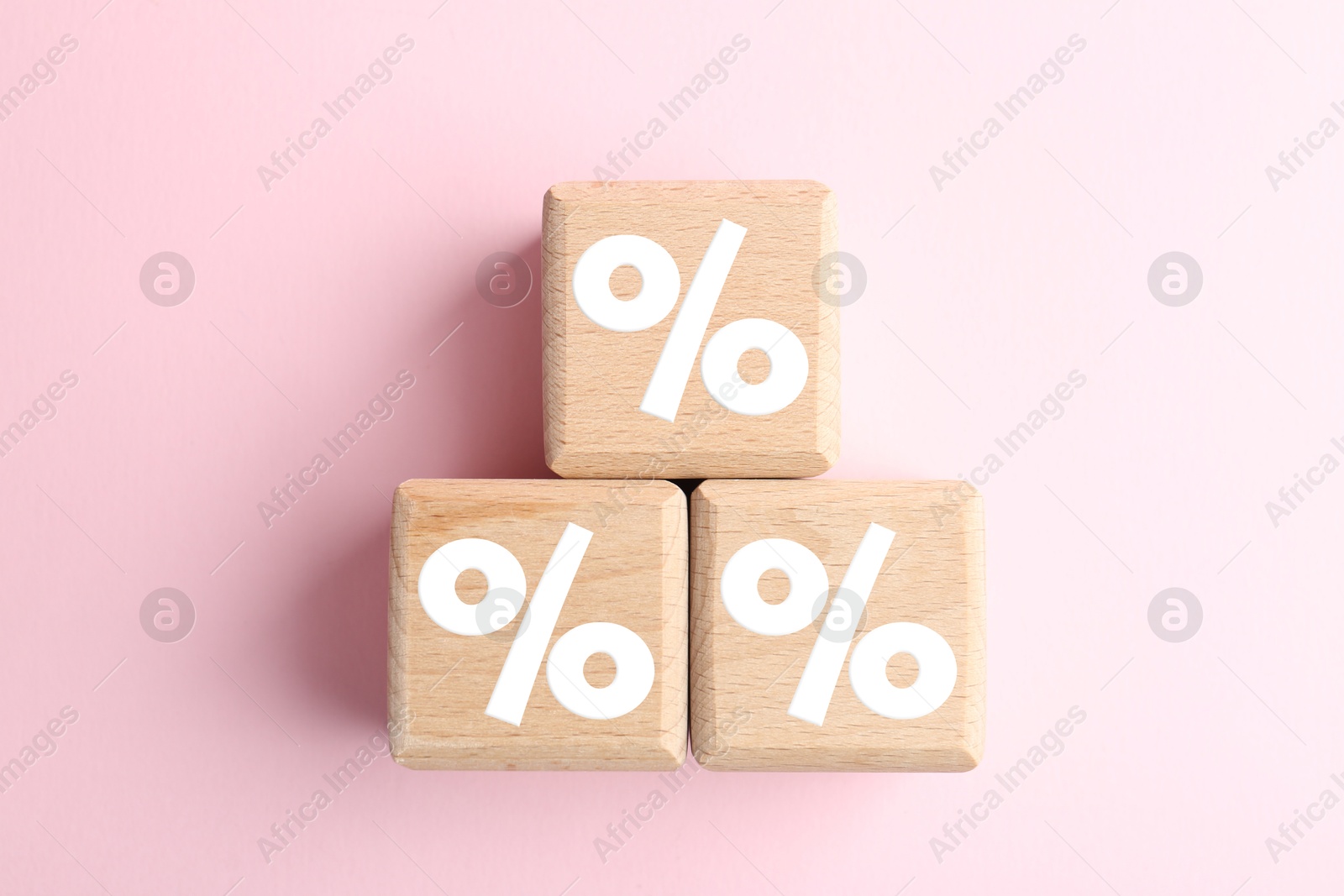 Image of Wooden cubes with percent signs on pink background, top view
