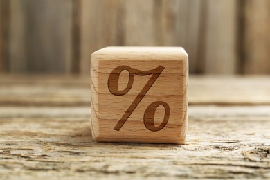 Image of Cube with percent sign on wooden table, closeup