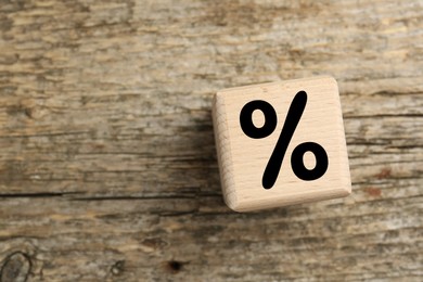 Image of Cube with percent sign on wooden table, top view. Space for text