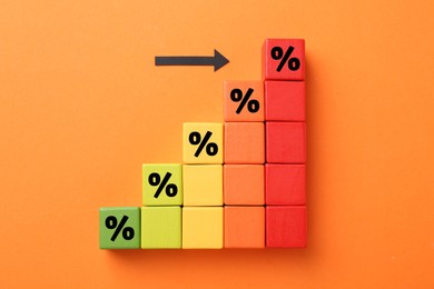 Image of Colorful cubes with percent signs and arrow on orange background, top view