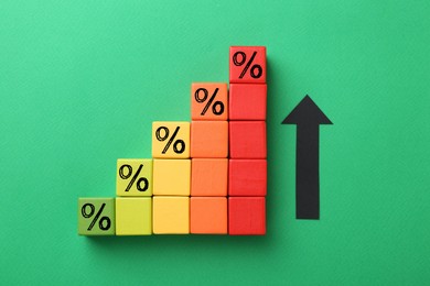 Image of Colorful cubes with percent signs and arrow on green background, top view