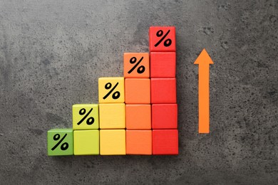 Image of Colorful cubes with percent signs and arrow on grey textured table, top view