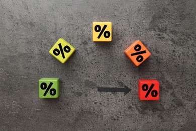 Image of Colorful cubes with percent signs and arrow on grey textured table, top view