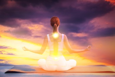 Image of Woman meditating in lotus position outdoors against sunset sky, double exposure. Sun shining in her. Yoga empowering inner world