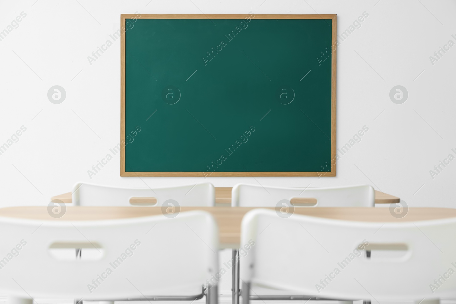 Blank green chalkboard, desks and chairs in classroom Photo of Blank green chalkboard, desks and chairs in classroom