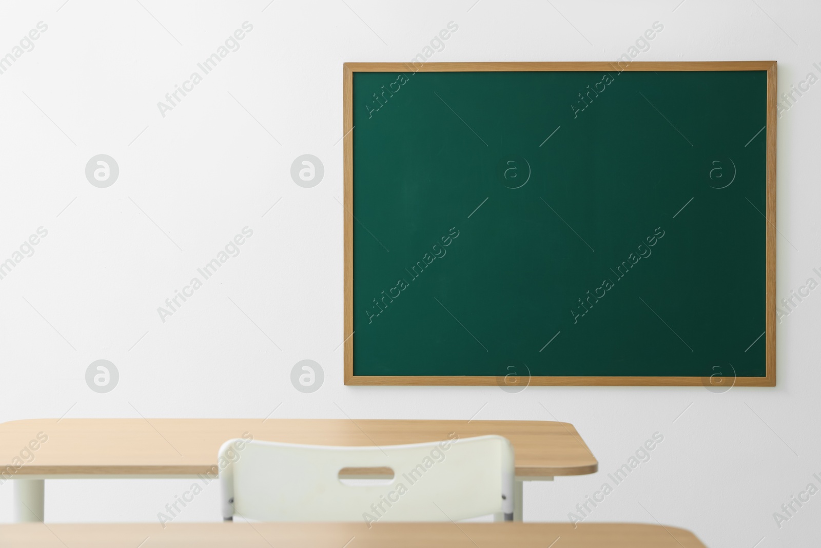 Blank green chalkboard, desks and chair in classroom Photo of Blank green chalkboard, desks and chair in classroom