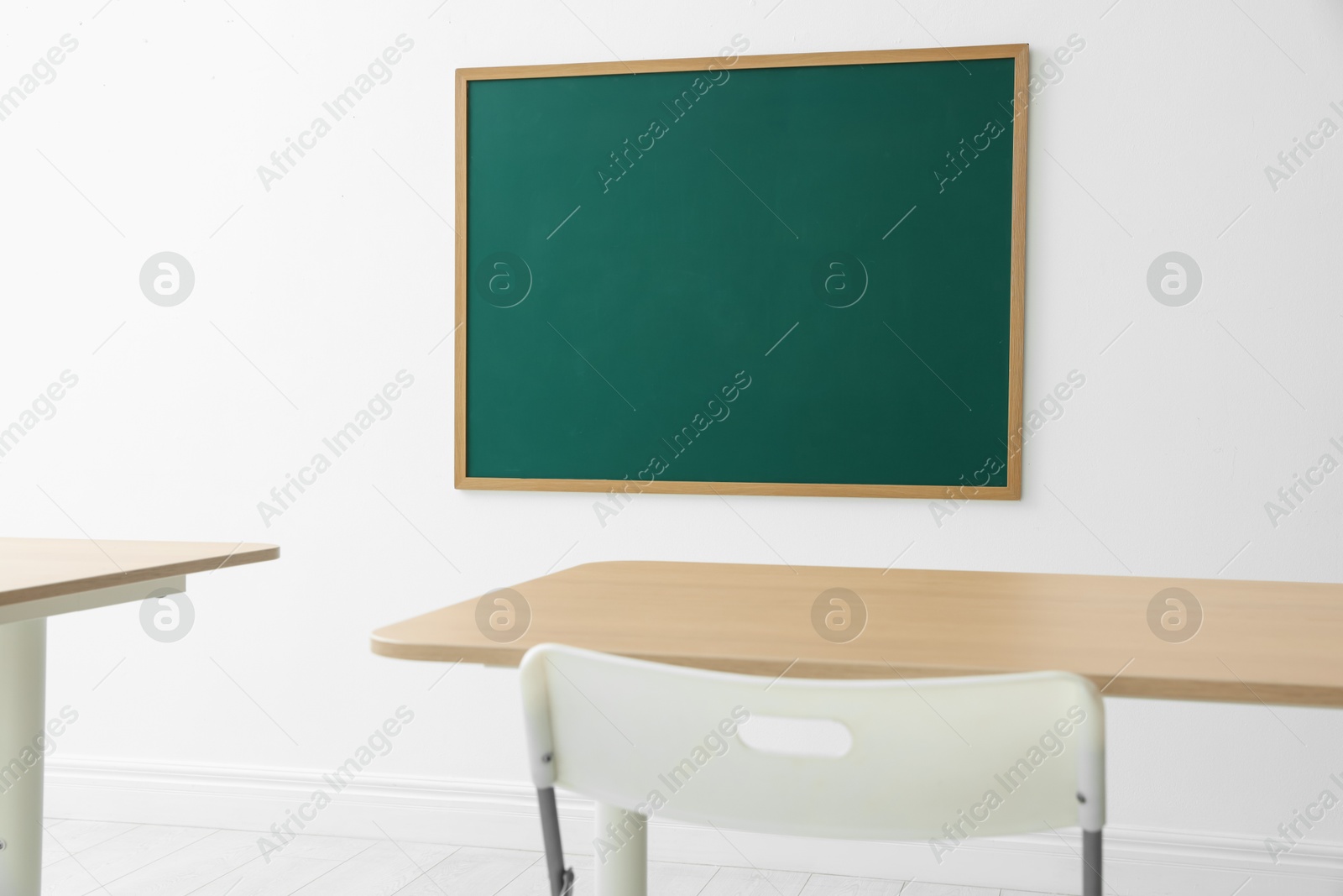 Blank green chalkboard, desks and chair in classroom Photo of Blank green chalkboard, desks and chair in classroom