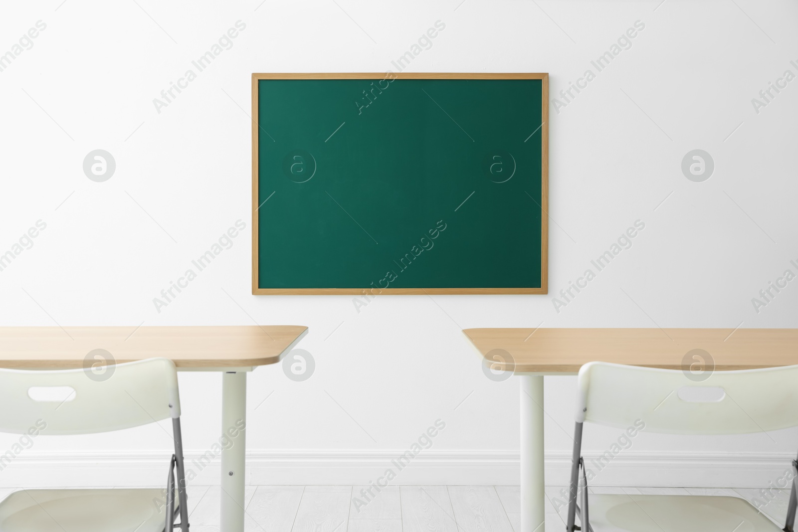 Blank green chalkboard, desks and chairs in classroom Photo of Blank green chalkboard, desks and chairs in classroom