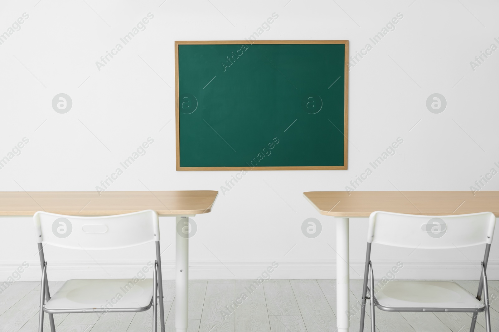Blank green chalkboard, desks and chairs in classroom Photo of Blank green chalkboard, desks and chairs in classroom