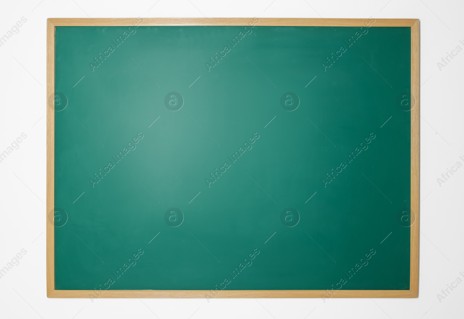 Photo of Blank green chalkboard on white wall indoors
