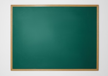 Photo of Blank green chalkboard on white wall indoors