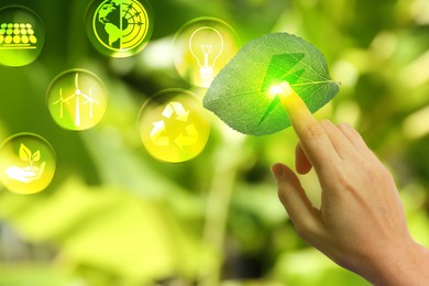 Image of Electricity and nature. Woman touching leaf with lightning symbol against blurred green background, closeup. Different icons