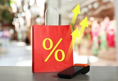 Image of Shopping bag with percent sign, arrows and payment terminal on counter in store