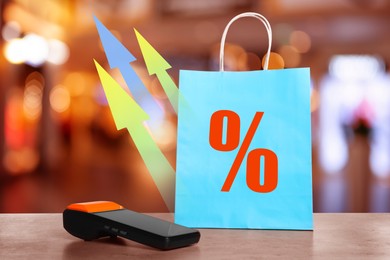 Image of Shopping bag with percent sign, arrows and payment terminal on counter in store