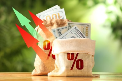 Image of Burlap bags with percent signs full of money and arrows against blurred green background