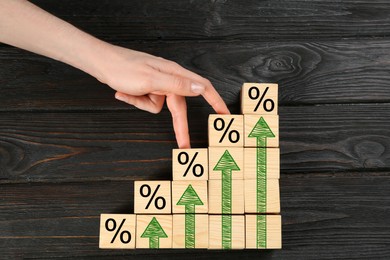 Image of Percent signs and arrows on wooden cubes, top view. Woman walking on ladder of cubes with fingers, closeup