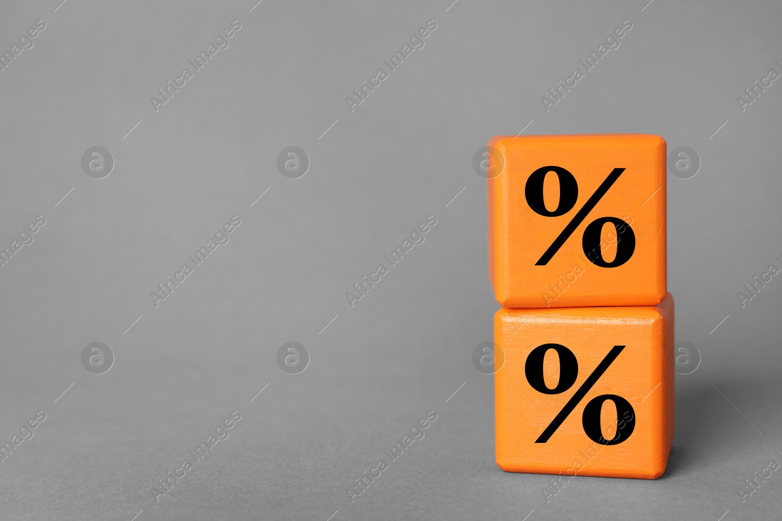 Image of Percent signs on orange cubes against grey background. Space for text