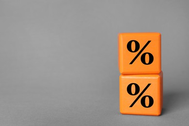 Image of Percent signs on orange cubes against grey background. Space for text