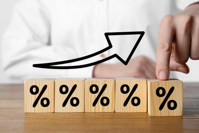 Image of Man touching wooden cube with percent sign among others at table, closeup
