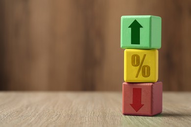 Image of Cubes with percent sign, up and down arrows on wooden table. Space for text