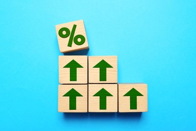 Image of Wooden cubes with percent sign and arrows on light blue background, top view
