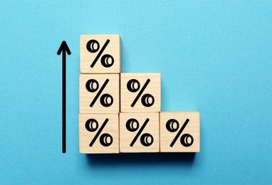 Image of Wooden cubes with percent signs and arrow on blue background, top view