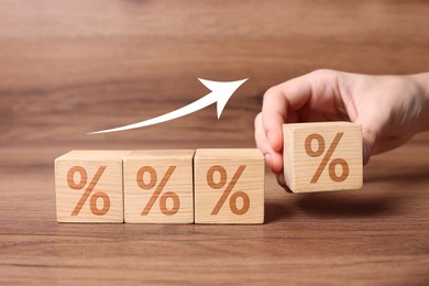Image of Man putting wooden cube with percent sign next to others on table, closeup