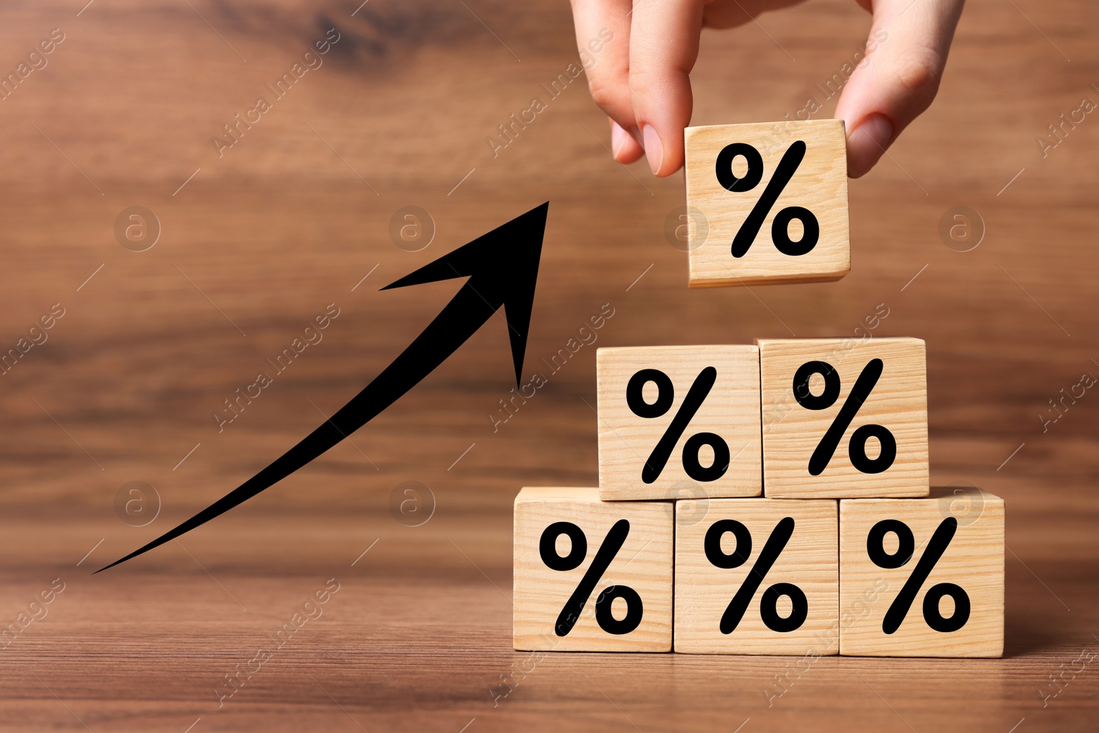 Man putting wooden cube with percent sign onto others on table, closeup Image of Man putting wooden cube with percent sign onto others on table, closeup