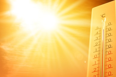 Image of Extremely high temperature on thermometer against orange sky on sunny day. Severely hot summer weather