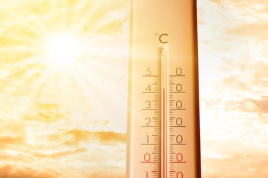 Image of High temperature on thermometer against orange sky on sunny day. Hot summer weather