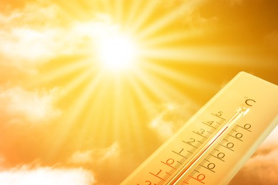 Image of Extremely high temperature on thermometer against orange sky on sunny day. Severely hot summer weather