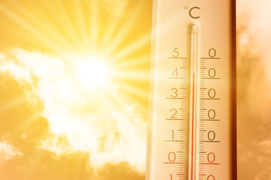 Image of High temperature on thermometer against orange sky on sunny day. Hot summer weather