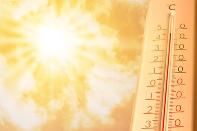Image of Extremely high temperature on thermometer against orange sky on sunny day. Severely hot summer weather