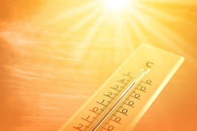 Image of Extremely high temperature on thermometer against orange sky on sunny day. Severely hot summer weather