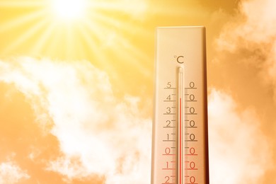 Image of High temperature on thermometer against orange sky on sunny day. Hot summer weather