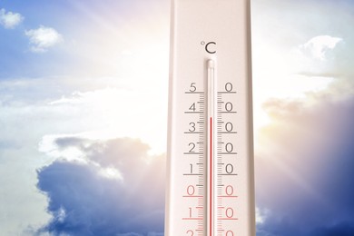 Image of High temperature on thermometer against blue sky on sunny day. Summer weather