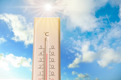 Image of High temperature on thermometer against blue sky on sunny day. Summer weather