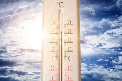 Image of High temperature on thermometer against blue sky on sunny day. Summer weather