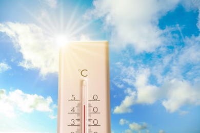 Image of Extremely high temperature on thermometer against blue sky on sunny day. Summer weather